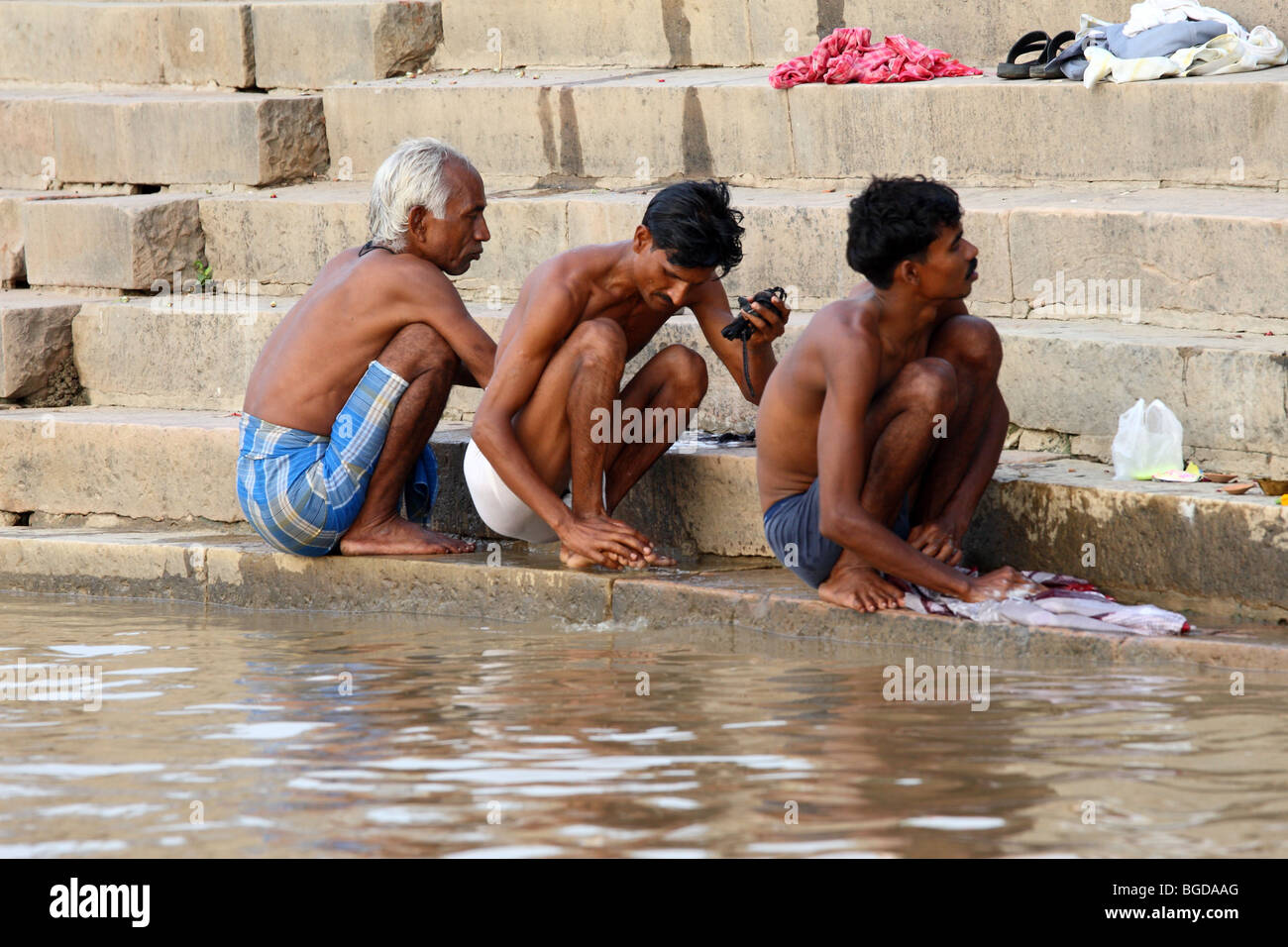 group of 3 men take morning bath in the gange river, varanasi, benares, india Stock Photo