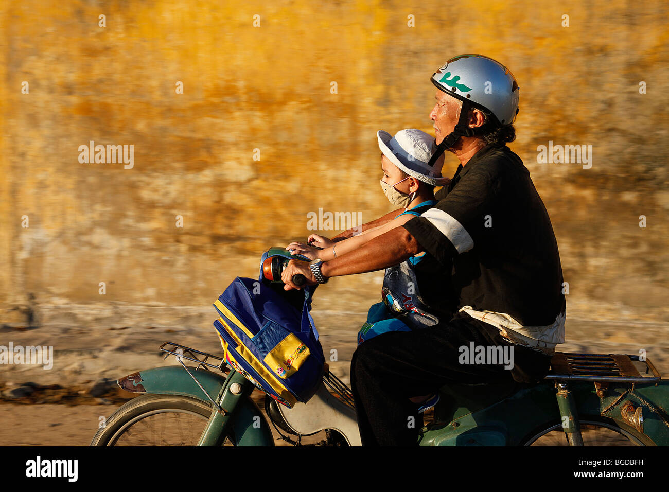 Vietnamese father with his son on his motor scooter with a backpack, Hoi An, Vietnam, Southeast Asia Stock Photo