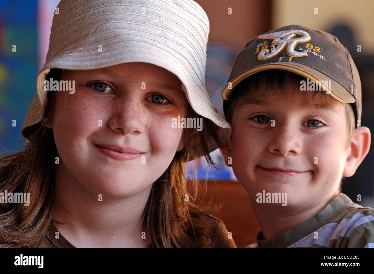 Portrait of a young girl with freckles and a hat and a young boy wearing a peaked cap Stock Photo
