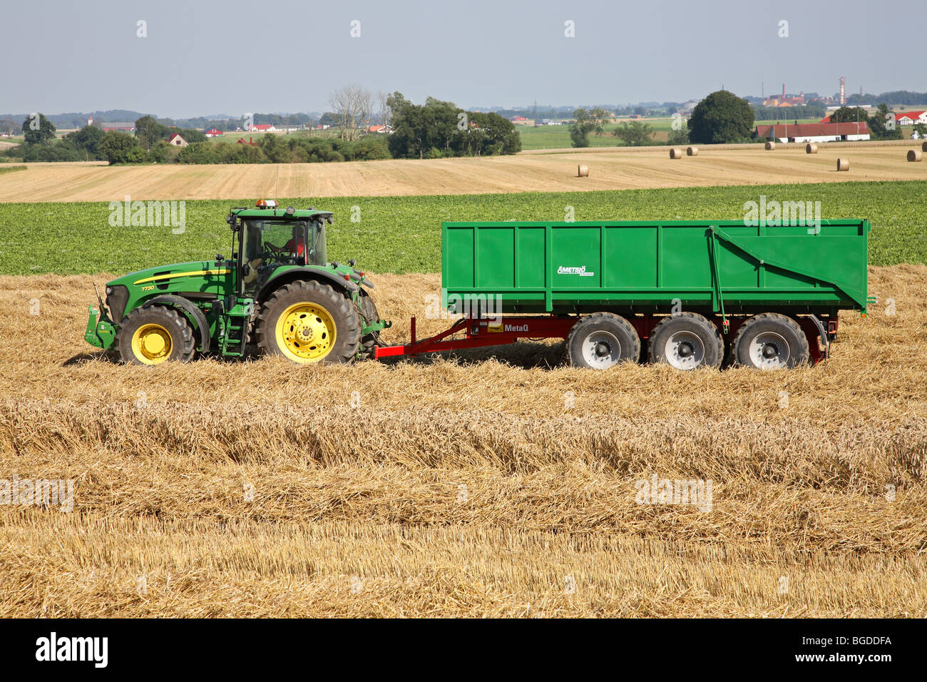 Tractor with trailer awaiting a load of wheat from a nearby combine during harvesting. South Sweden, Scandinavia. Stock Photo