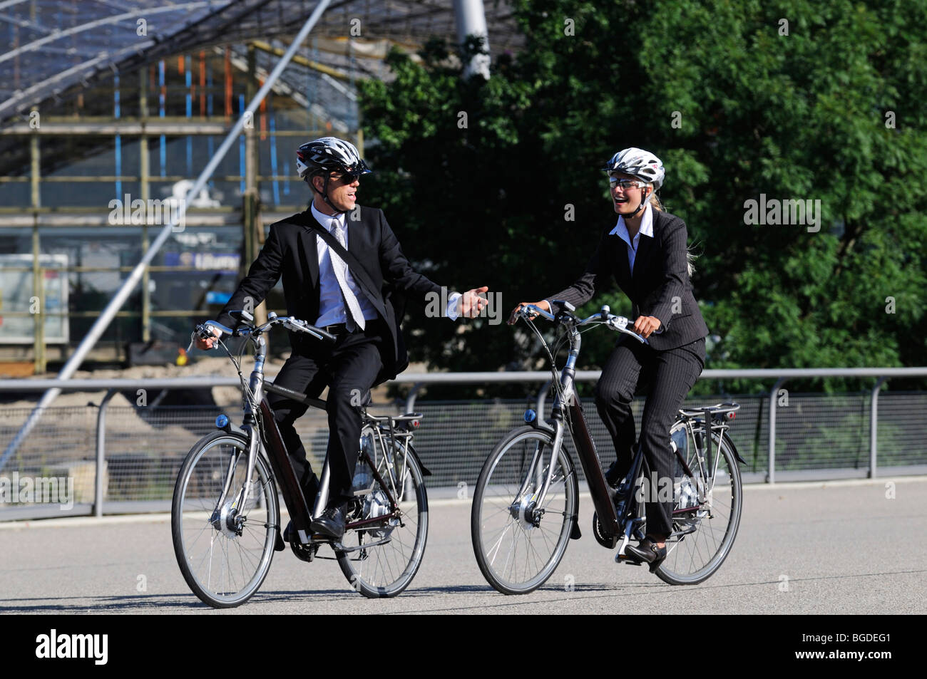 Business people riding on electric bicycles, pedelecs, Olympic Stadium, Munich, Bavaria, Germany, Europe Stock Photo