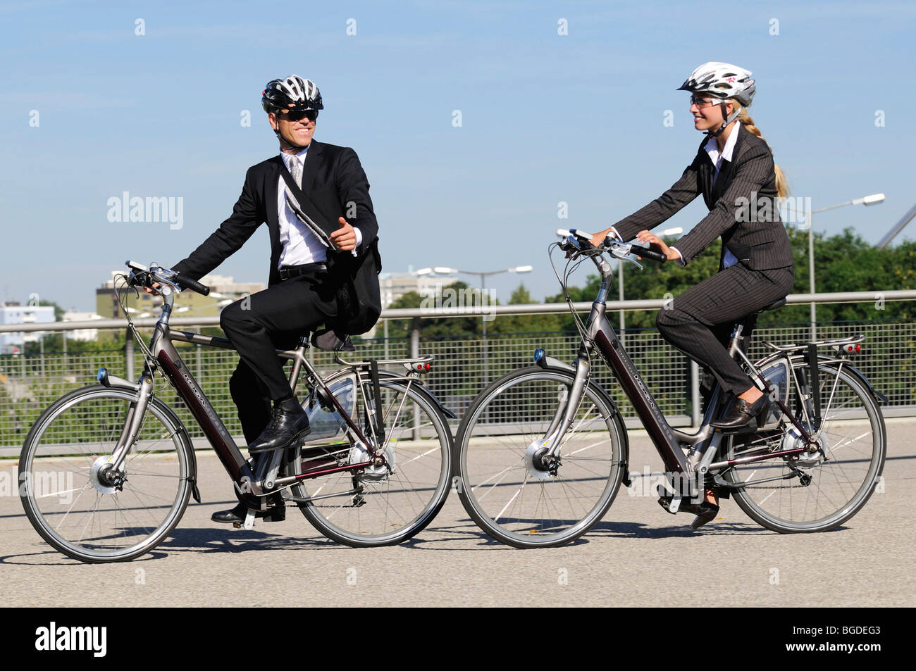 Business people riding on electric bicycles, pedelecs, Olympic Stadium, Munich, Bavaria, Germany, Europe Stock Photo