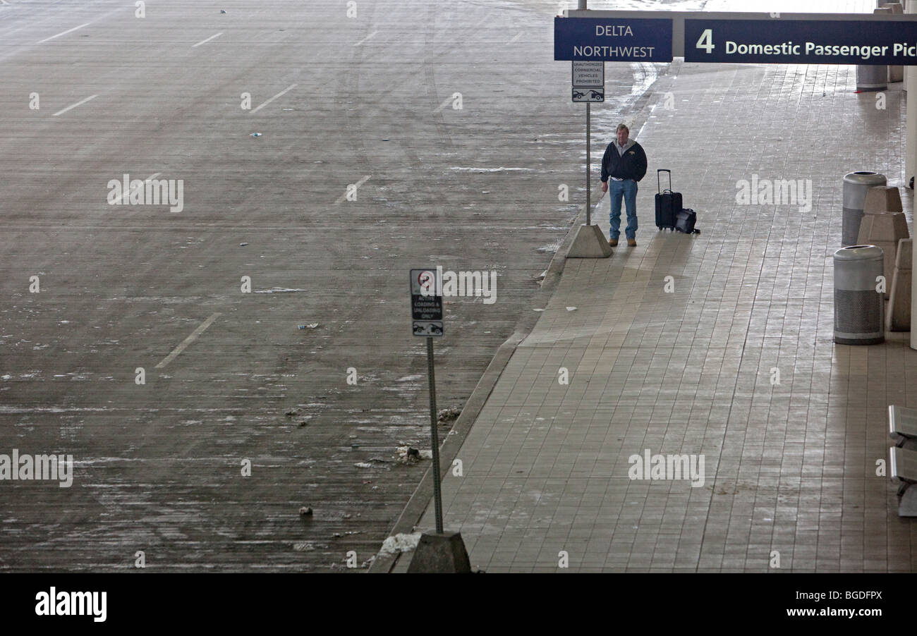 Romulus, Michigan - A traveler waits to be picked up after arriving on a flight at Detroit Metropolitan Airport. Stock Photo