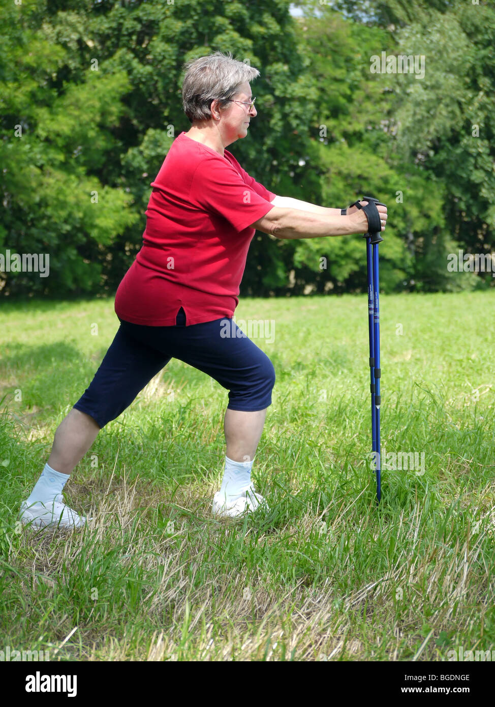 Senior woman doing a series of warm-up exercises with walking poles Stock Photo