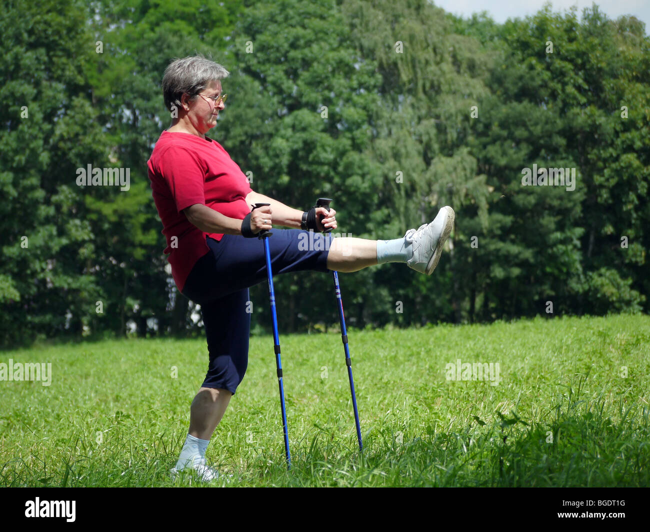Senior woman doing a series of warm-up exercises with walking poles