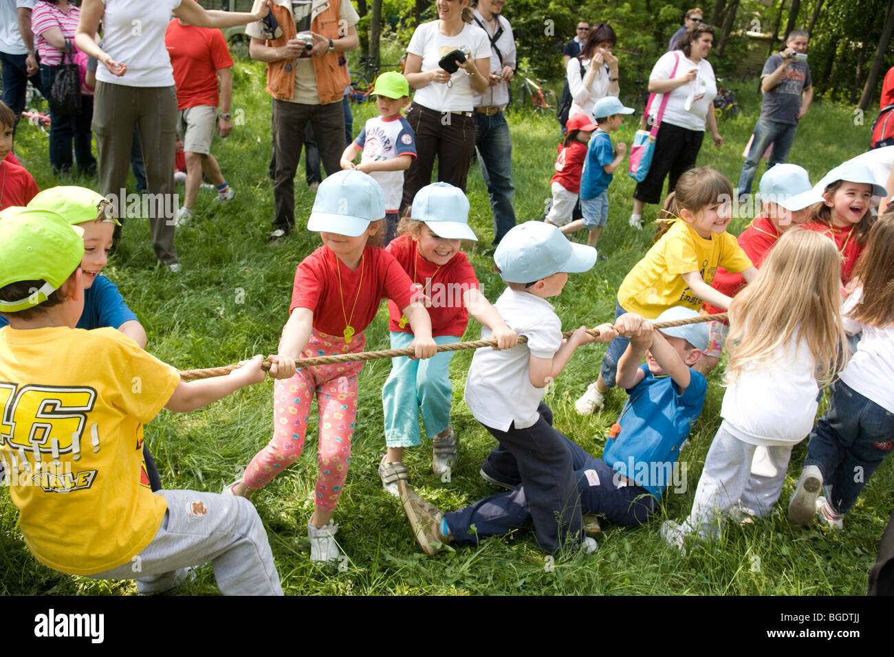 preschool-children-playing-tug-of-war-with-parents-watching-stock-photo