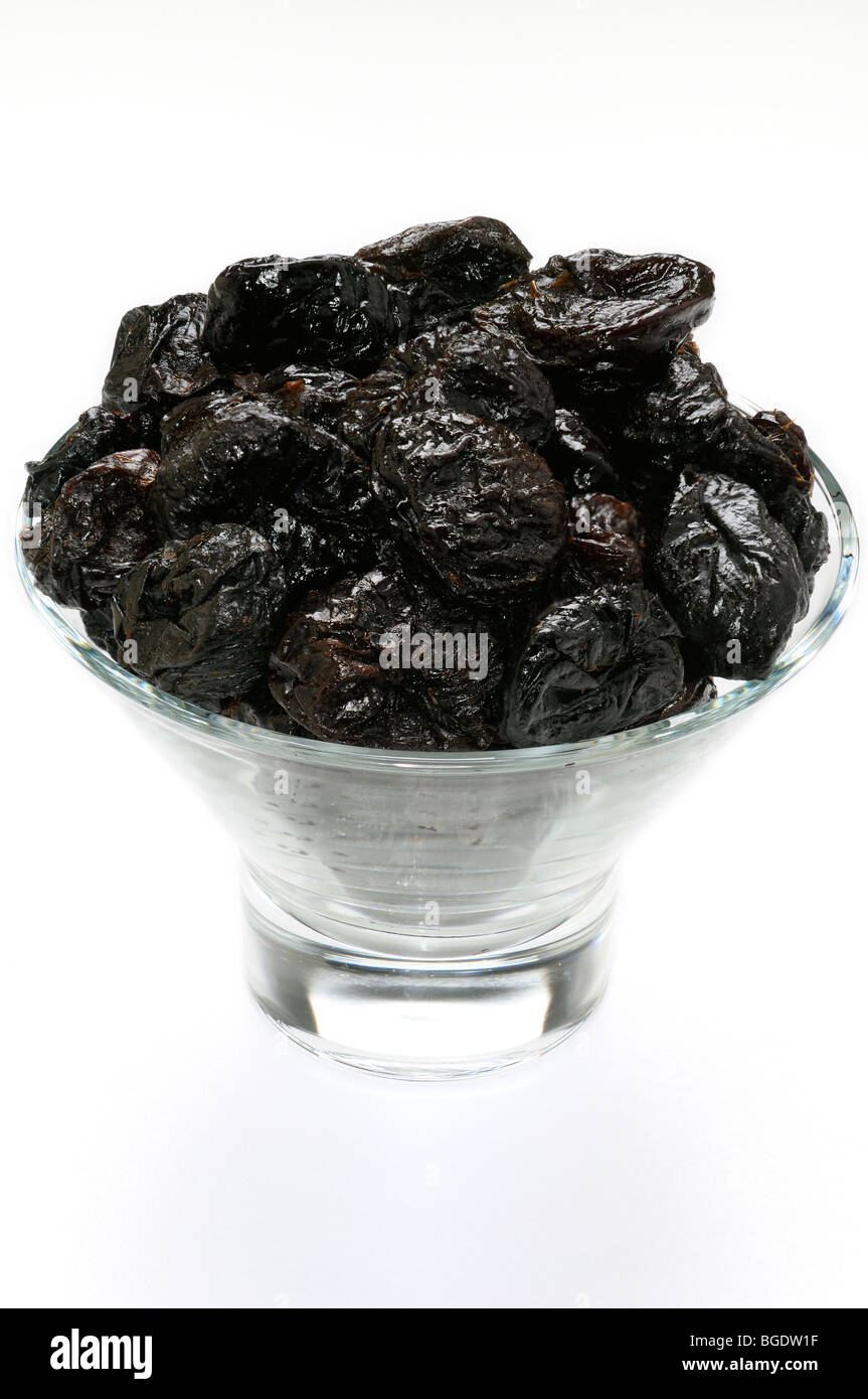 Glass bowl of shiny prunes a natural laxative snack on a white background Stock Photo