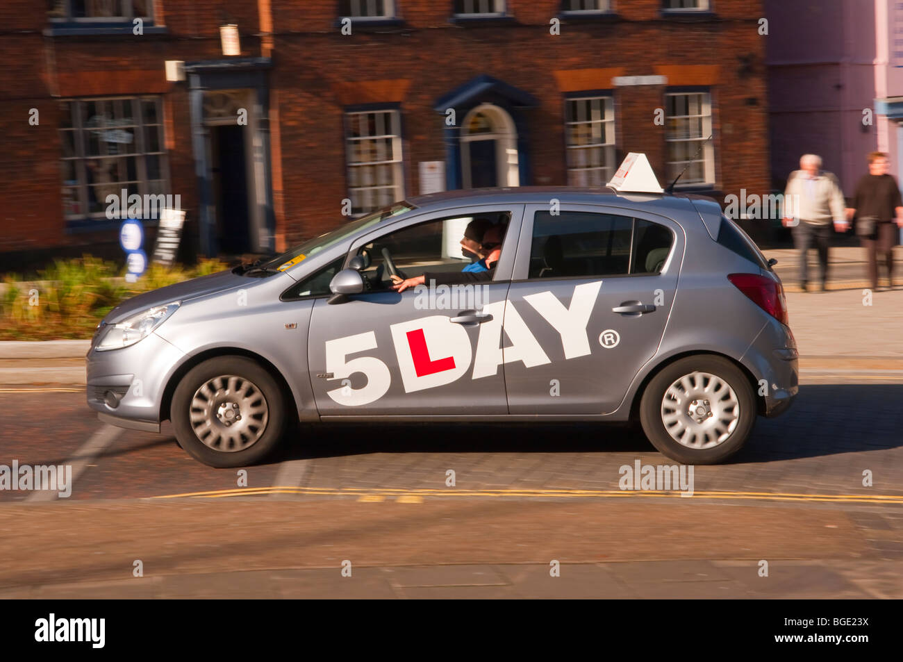A 5 day learner driver in a driving school car speeds past showing movement in Norwich,Norfolk,Uk Stock Photo