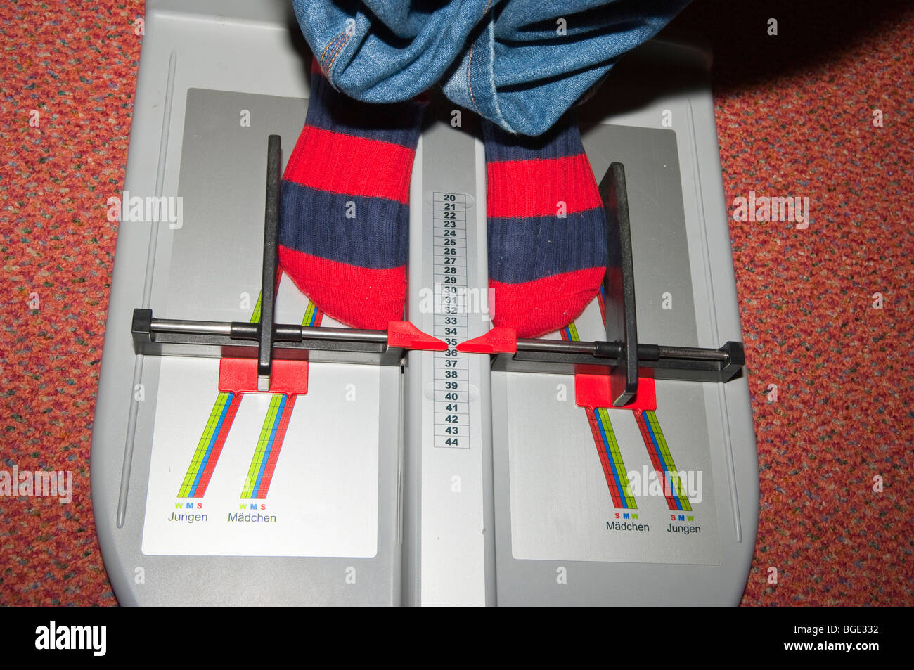 A shop assistant measures a childs feet for fitting new shoes in a Uk