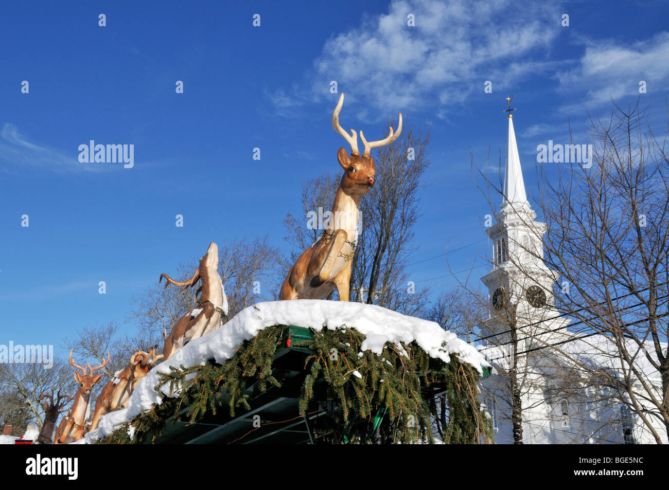 Rudolph the red nosed reindeer Christmas display outdoors with snow and church steeple Stock Photo