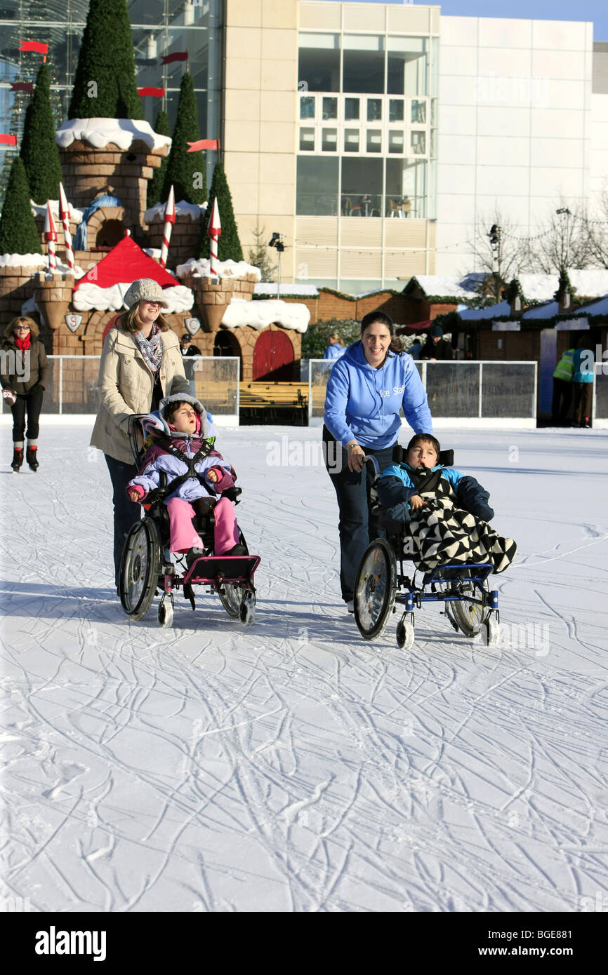 Disabled children in wheelchairs being pushed around an ice rink by