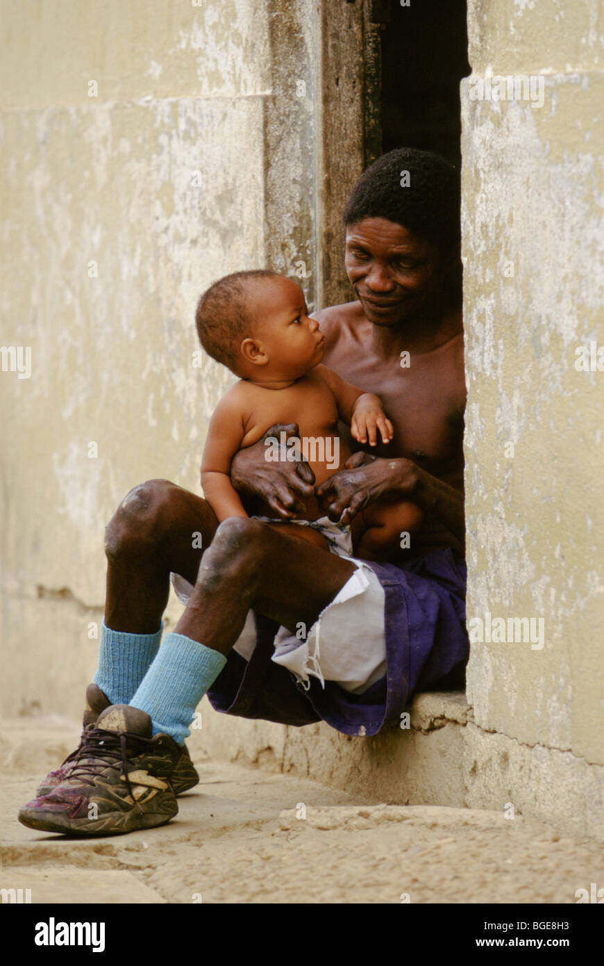 A resident in a leper colony in Luanda, Angola, holds his young son. Stock Photo