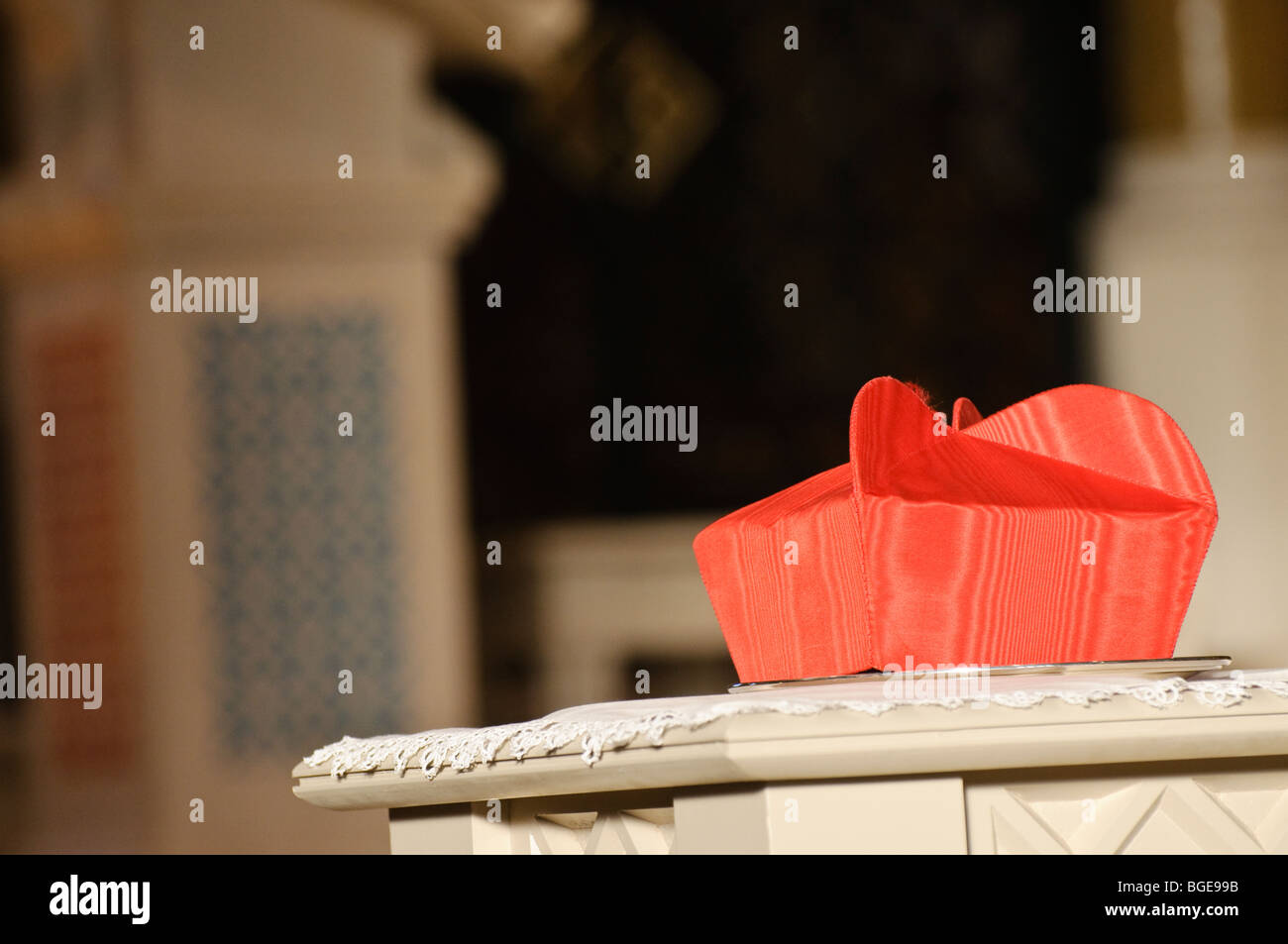 A cardinal's Biretta hat sits on a table during a requiem mass Stock Photo