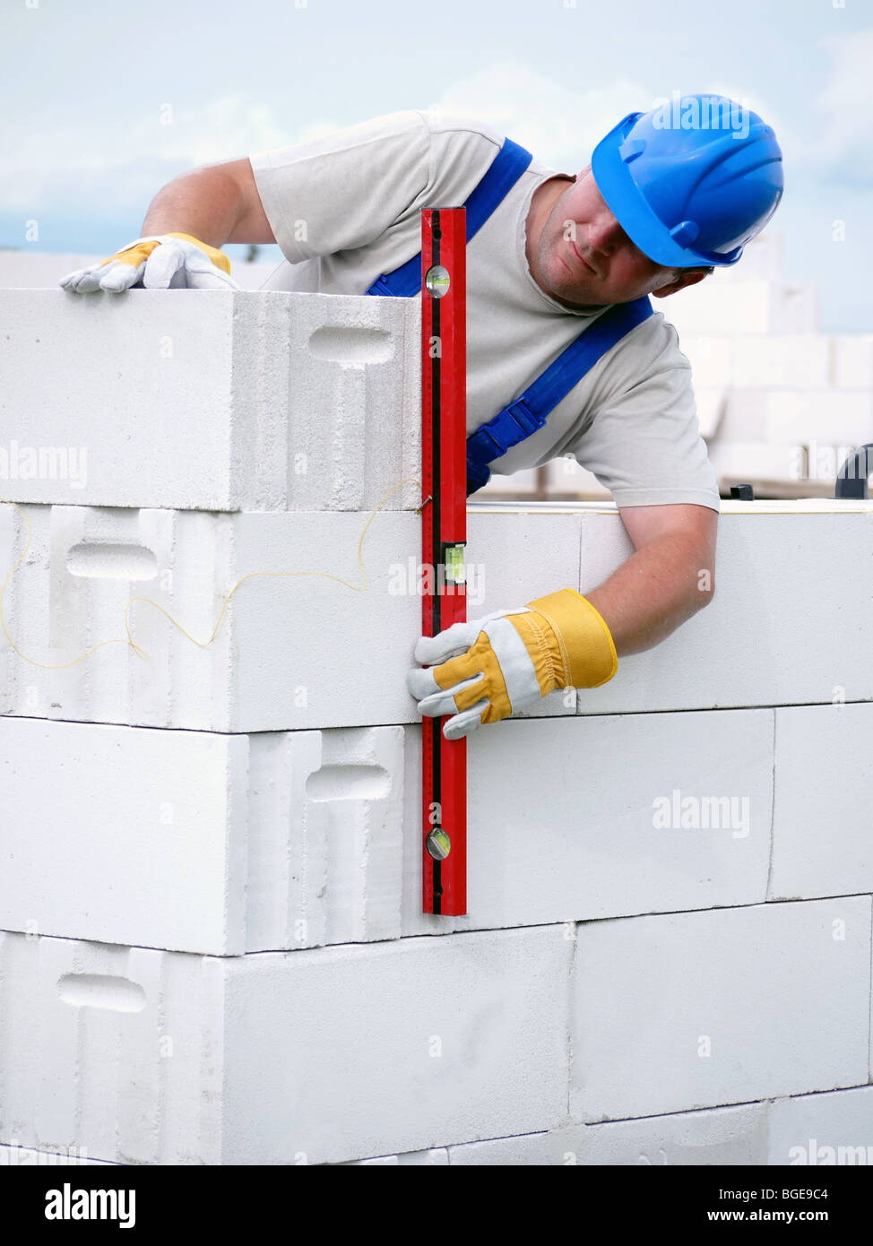Mason checking plumb line of house wall being made from aerated