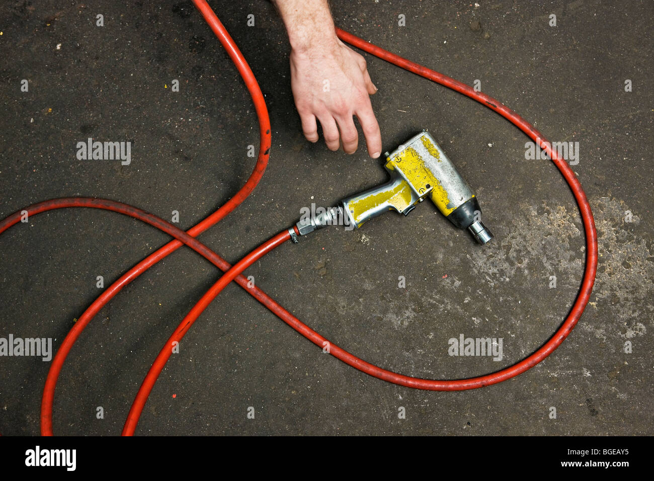 Man grabing compressed air tool from the floor. Stock Photo