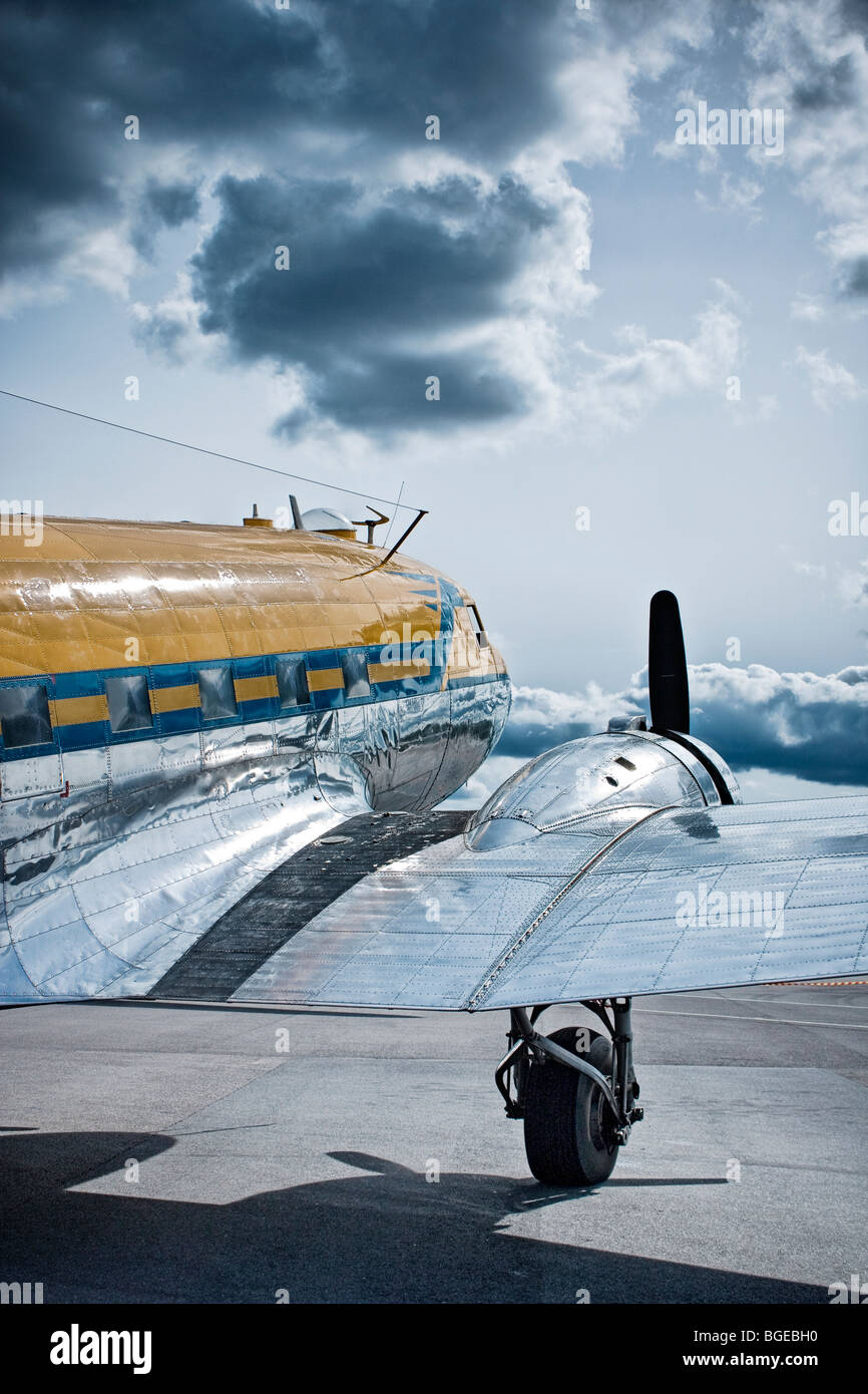 A propeller-driven aircraft  DC3shining in the sun as the clouds disperse. Stock Photo