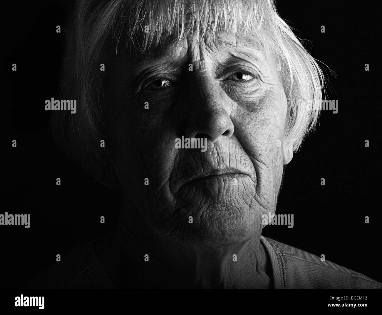a distressed older lady in dramatic low key black and white Stock Photo