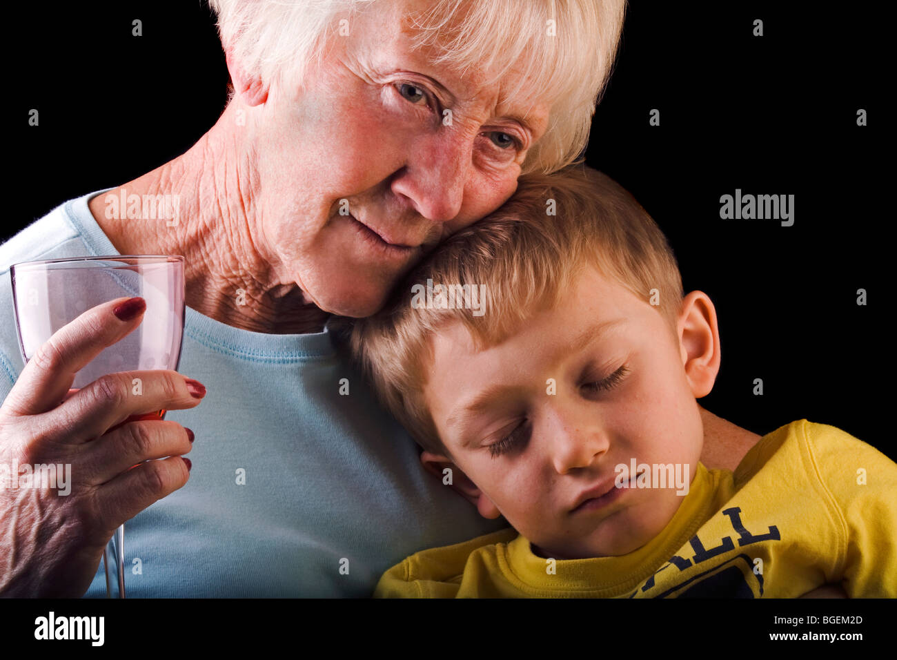a loving grandmother holds her sleeping grandson on her lap Stock Photo