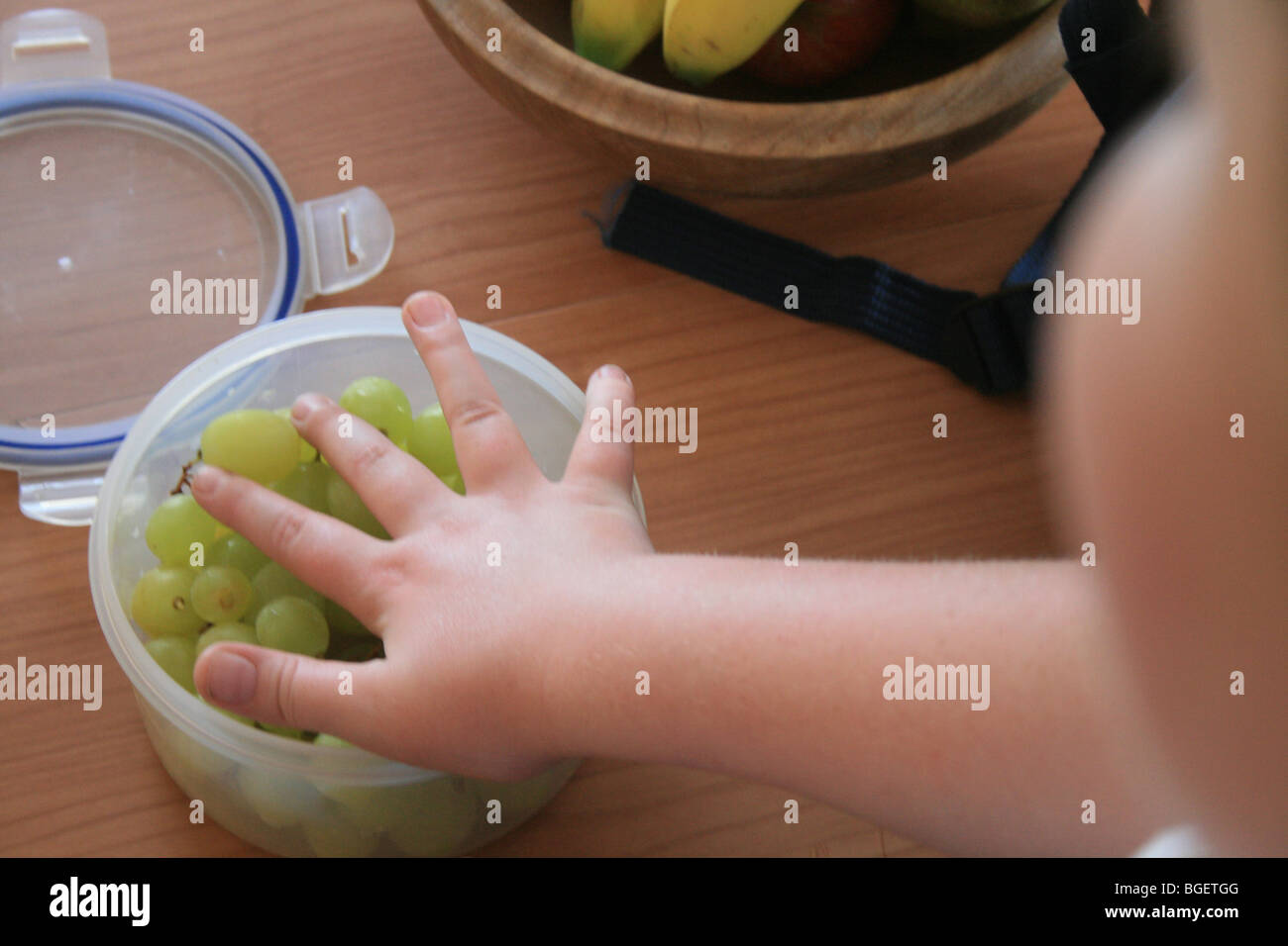 Grapes in a Tupperware bowl about to be grabbed Stock Photo Alamy