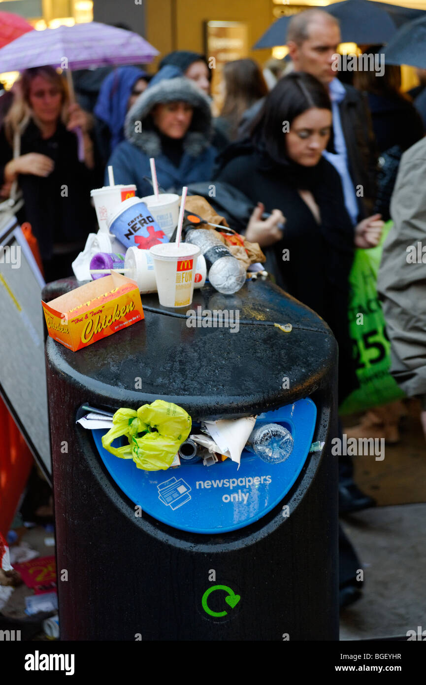 Overflowing public newspaper recycling bin with mixed waste. London. Britain. UK Stock Photo