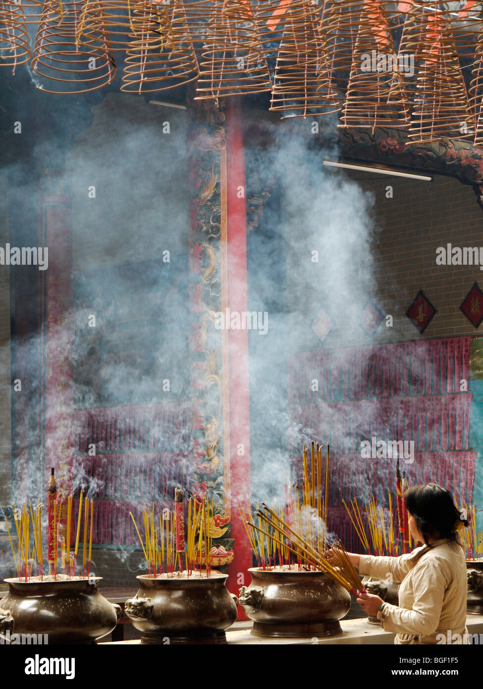Worshiper lights Incense sticks in Buddhist Thein Hau Temple, Ho Chi Min City Vietnam December 2009 Stock Photo
