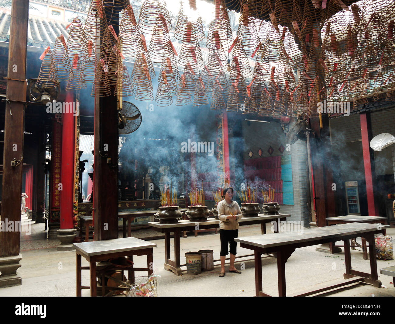 Worshiper lights Incense sticks in Buddhist Thein Hau Temple, Ho Chi Min City Vietnam December 2009 Stock Photo