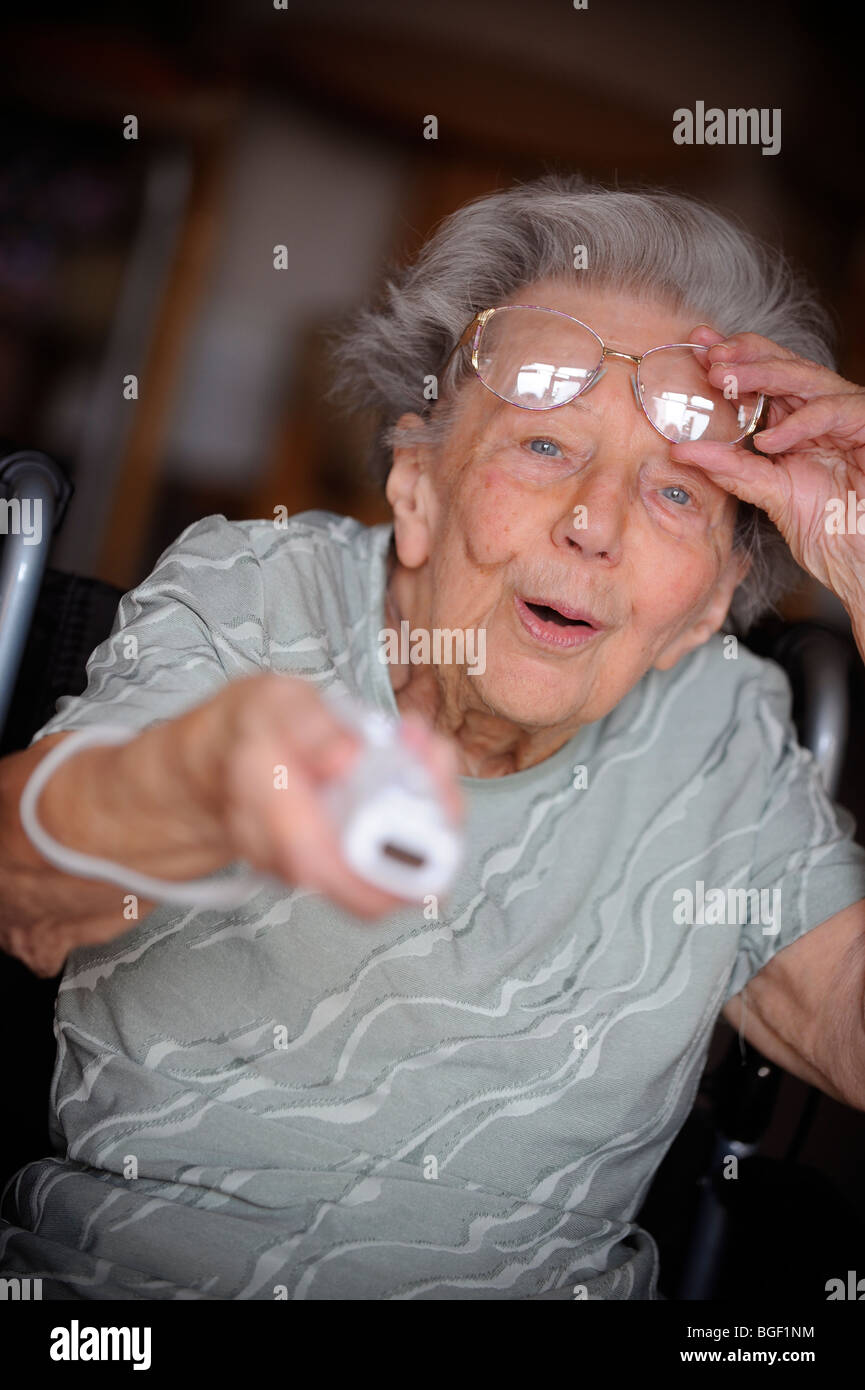 A pensioner lifts her spectacles whilst playing the Nintendo Wii. Stock Photo