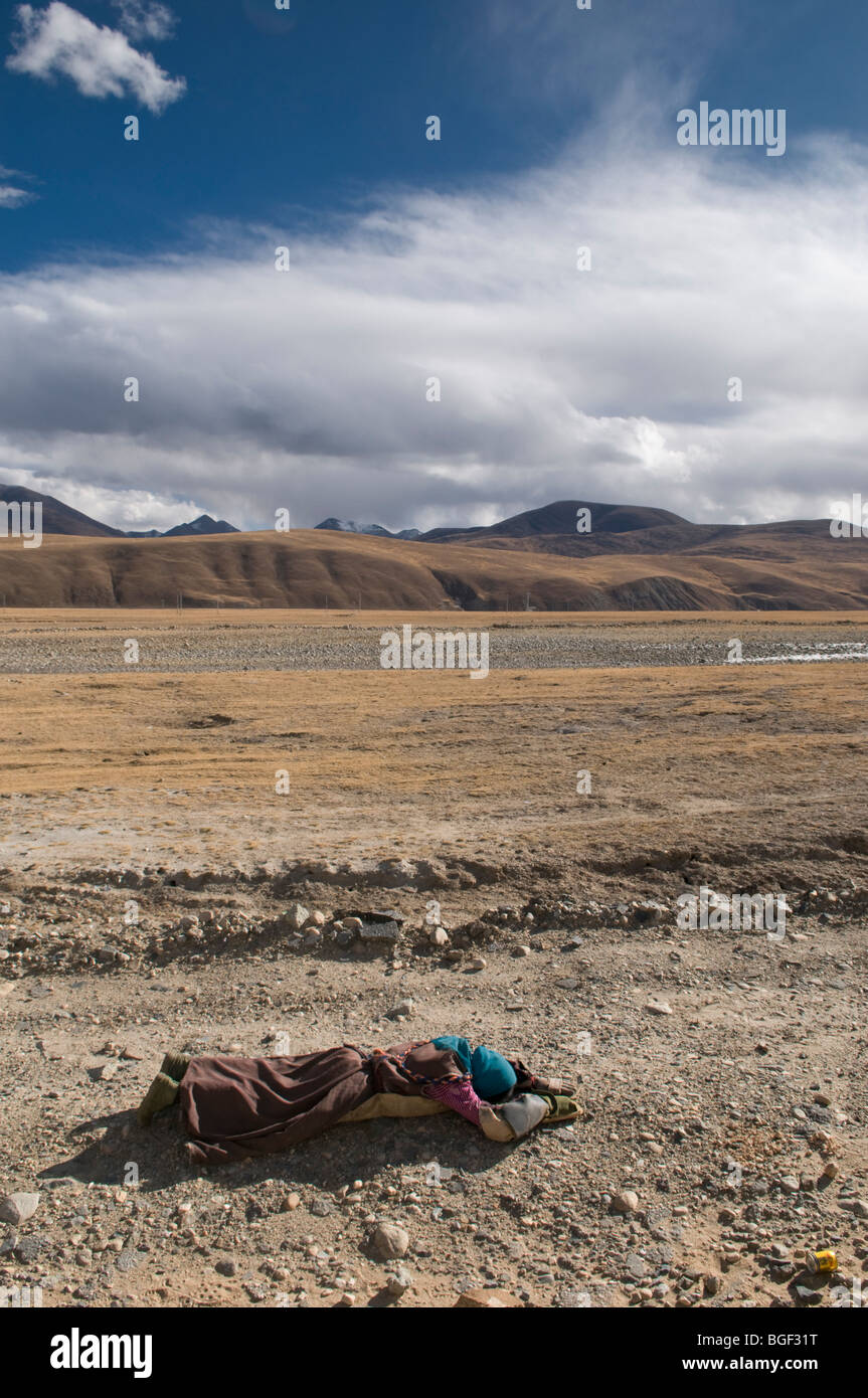 A devout Tibetan pilgrim prostrates along the high plateau  of Tibet on her way to the Jokang temple in Lhasa. Stock Photo