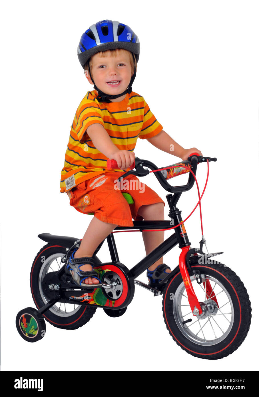 Boy on a bicycle with stabilisers, bike with stabilizer, child learning to ride a bike with stabilizers, learn to cycle Stock Photo