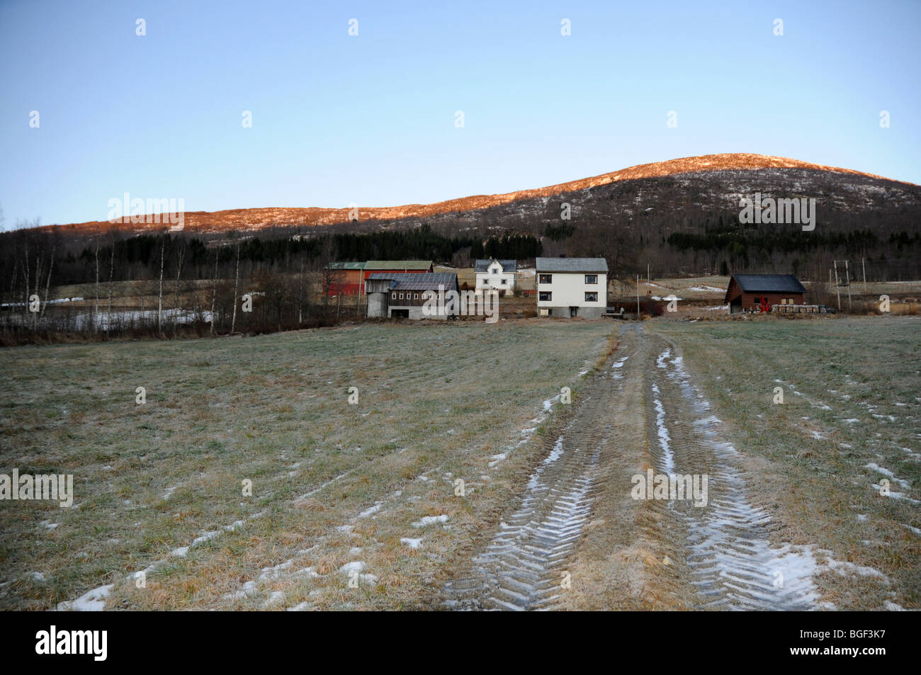 A mountain farm in Norway with the low sun on the mountain behind, winter Stock Photo