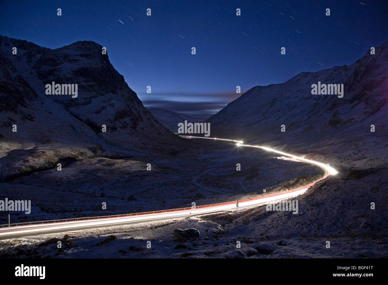 Traffic moves through the Pass of Glencoe, Scotland at night fall following the end of the Christmas holidays. Stock Photo