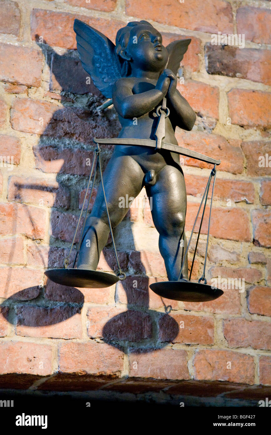 Brass winged Putto, with weighing scales, on a wall at Wawel Castle. Krakow, Poland. Stock Photo