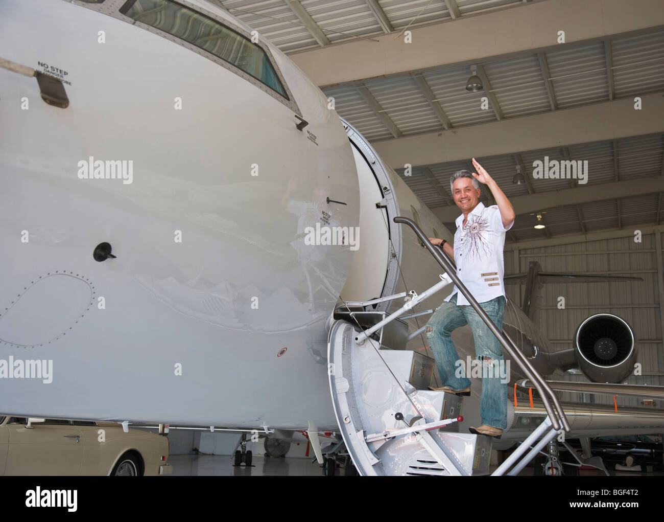 Man climbing up a jet stairs in hangar, smiling, Portrait. Aero Toy