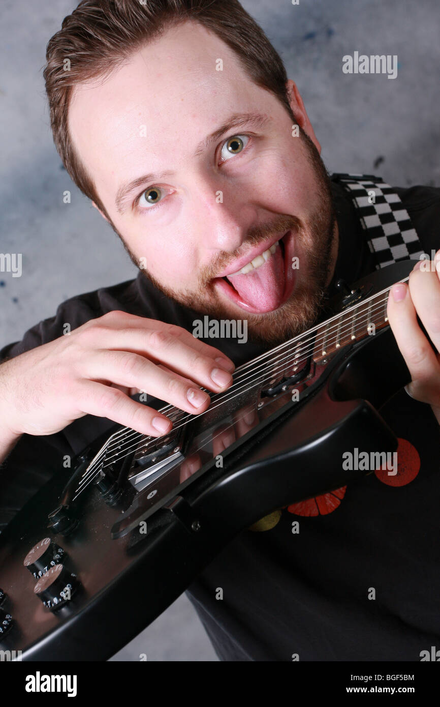 Unique perspective of a man playing a guitar, sticking out his tongue Stock Photo Alamy