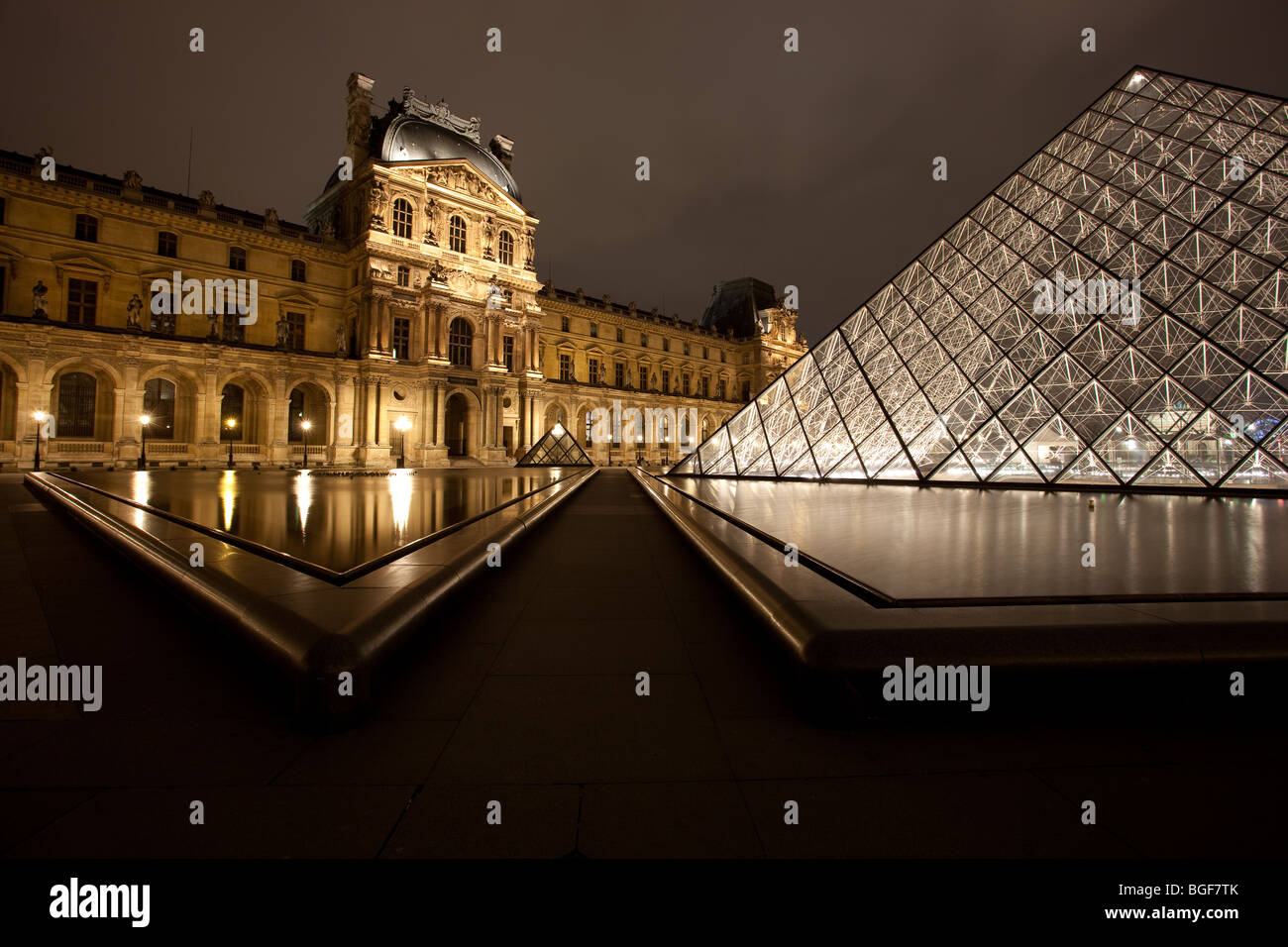 Louvre Museum and Triangle Pyramid lit up at night with fountain Stock Photo