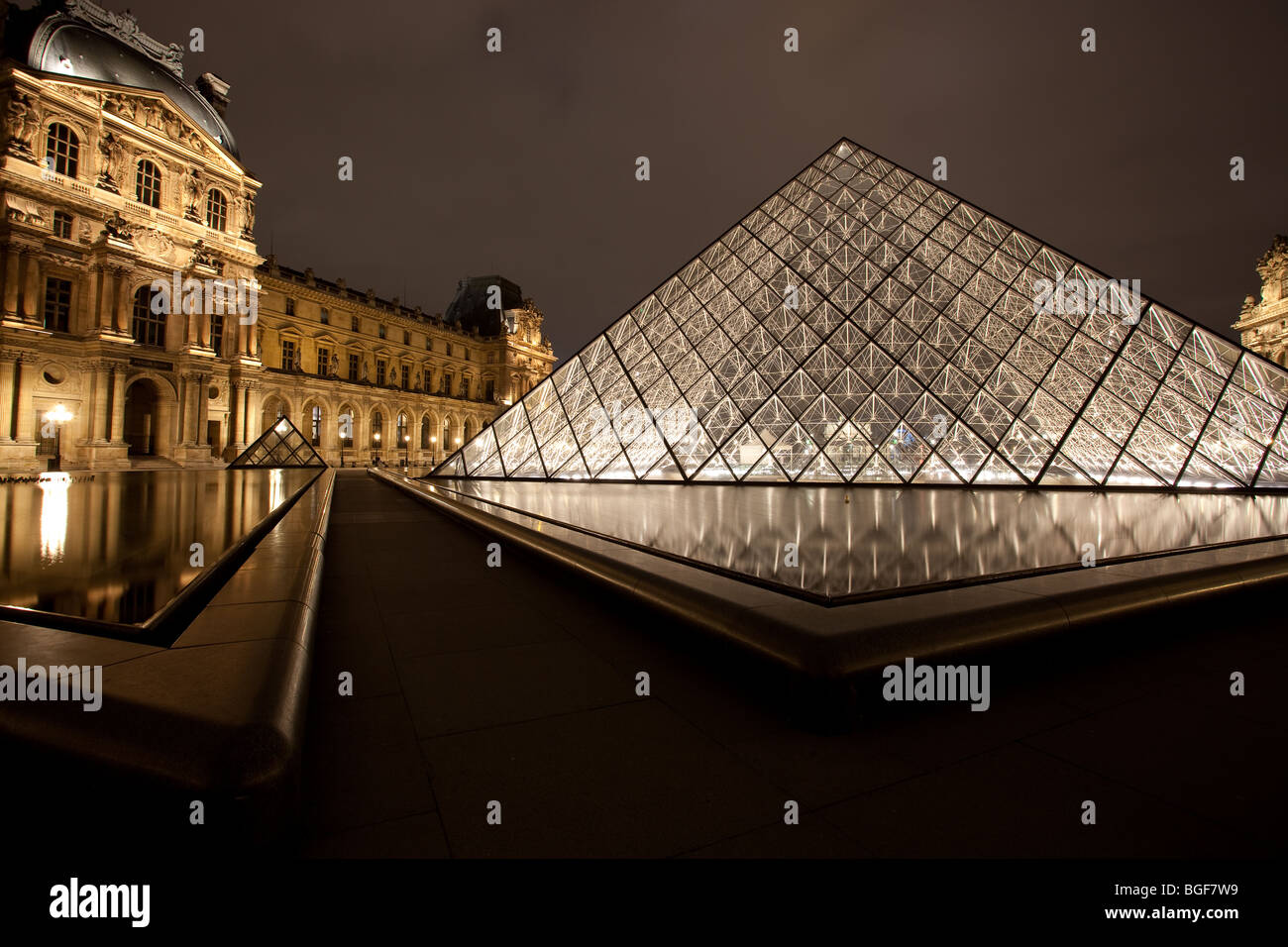 Louvre Museum and Triangle Pyramid lit up at night with fountain Stock Photo