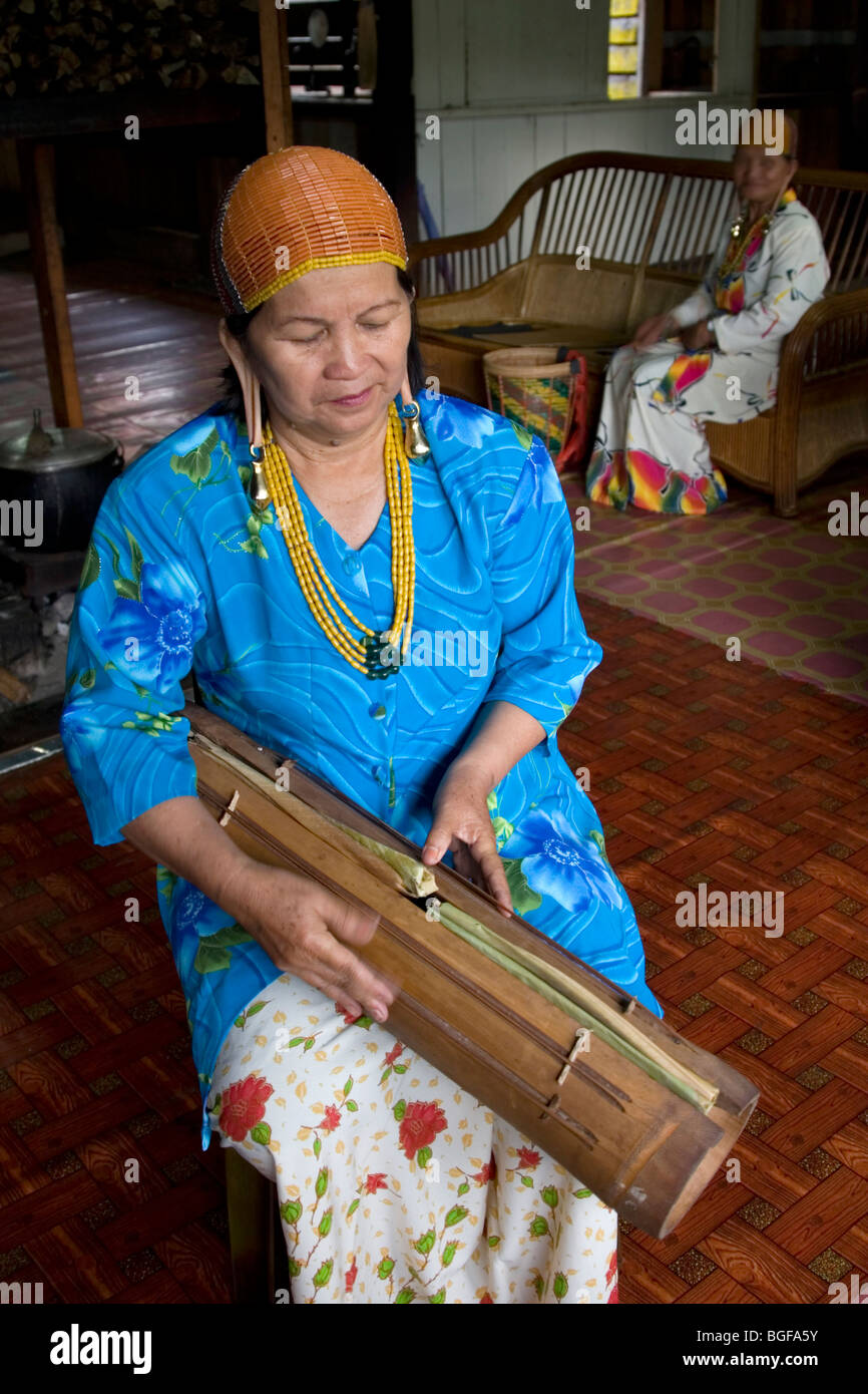 A Kelabit woman plays a traditional stringed bamboo instrument in the ...