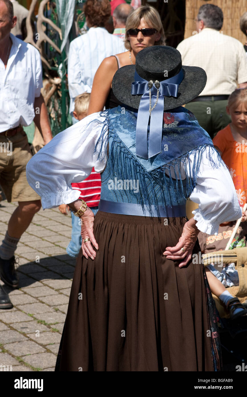Old woman standing having her hands on her waist as tourists roaming in the market in Bavaria, Germany Stock Photo