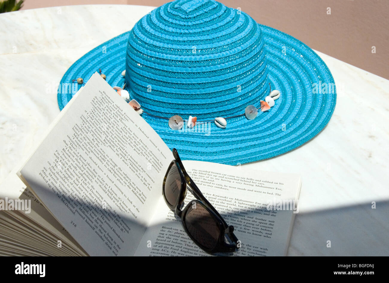 Sun hat, sunglasses and paperback book on table Stock Photo Alamy
