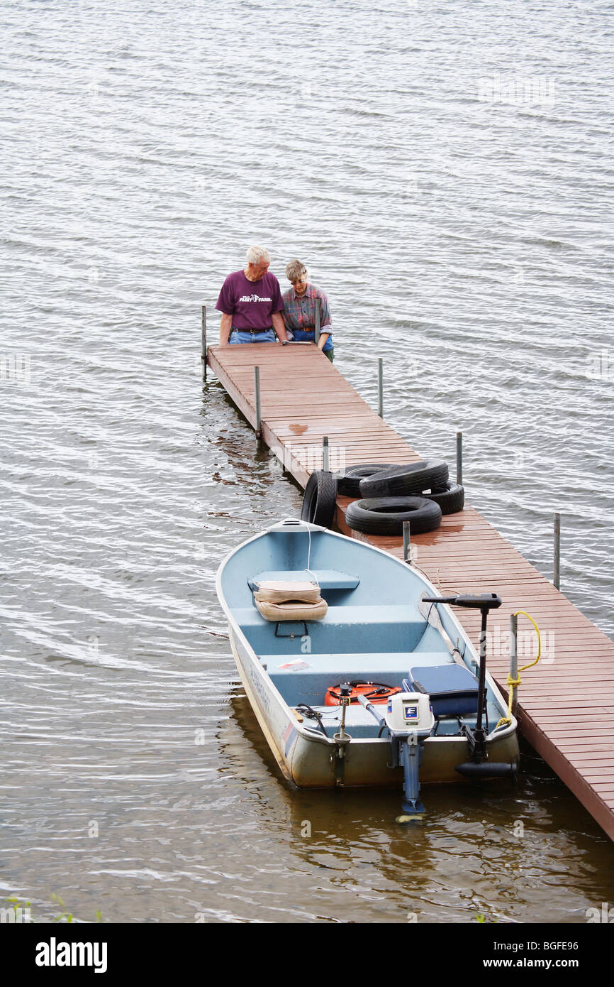 man and woman standing in lake raising boat dock alumnacraft fishing boat Stock Photo