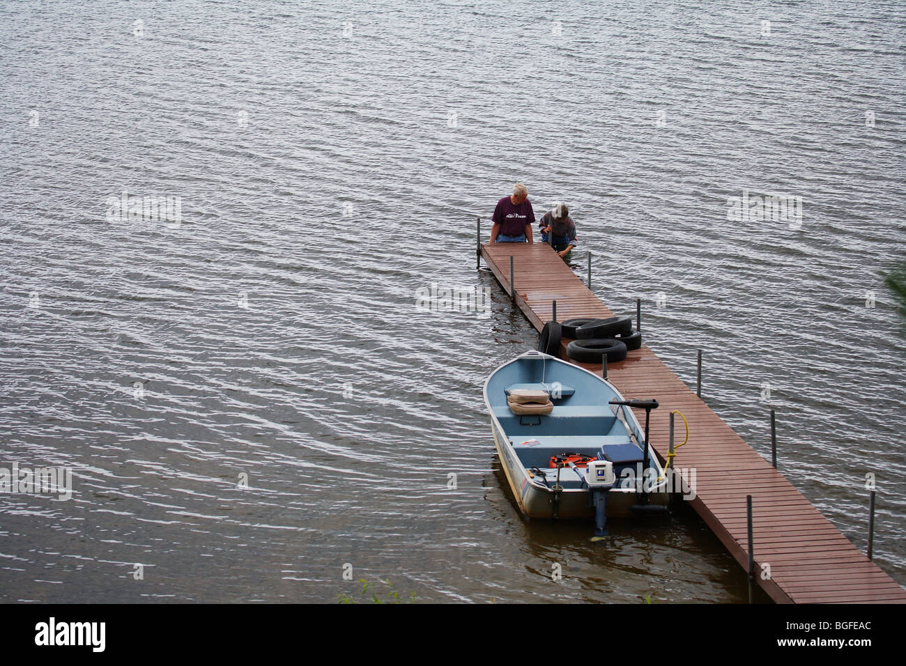man and woman standing in lake raising boat dock alumnacraft fishing boat Stock Photo