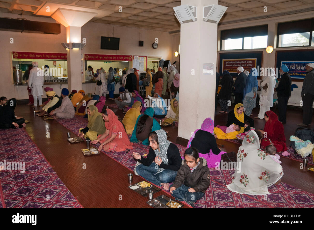 Sikhs enjoy the free vegetarian food provided in the Langar (community kitchen) in Hounslow Gurdwara before Vaisakhi procession Stock Photo