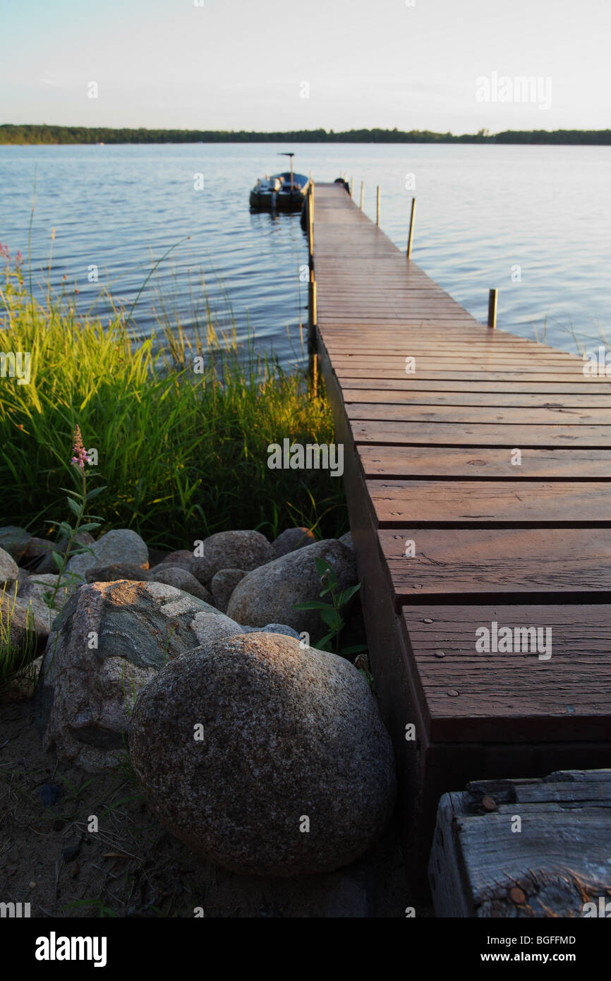 Wooden ramp leading to fishing boat and boat dock on fishing lake flowers water Stock Photo