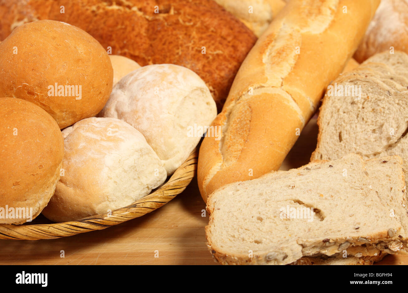 A breadbasket with rolls on a breadboard with sliced and unsliced