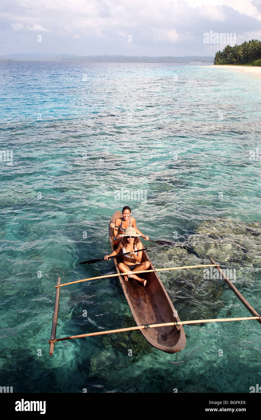 Two young woman paddling an outrigger dugout canoe 