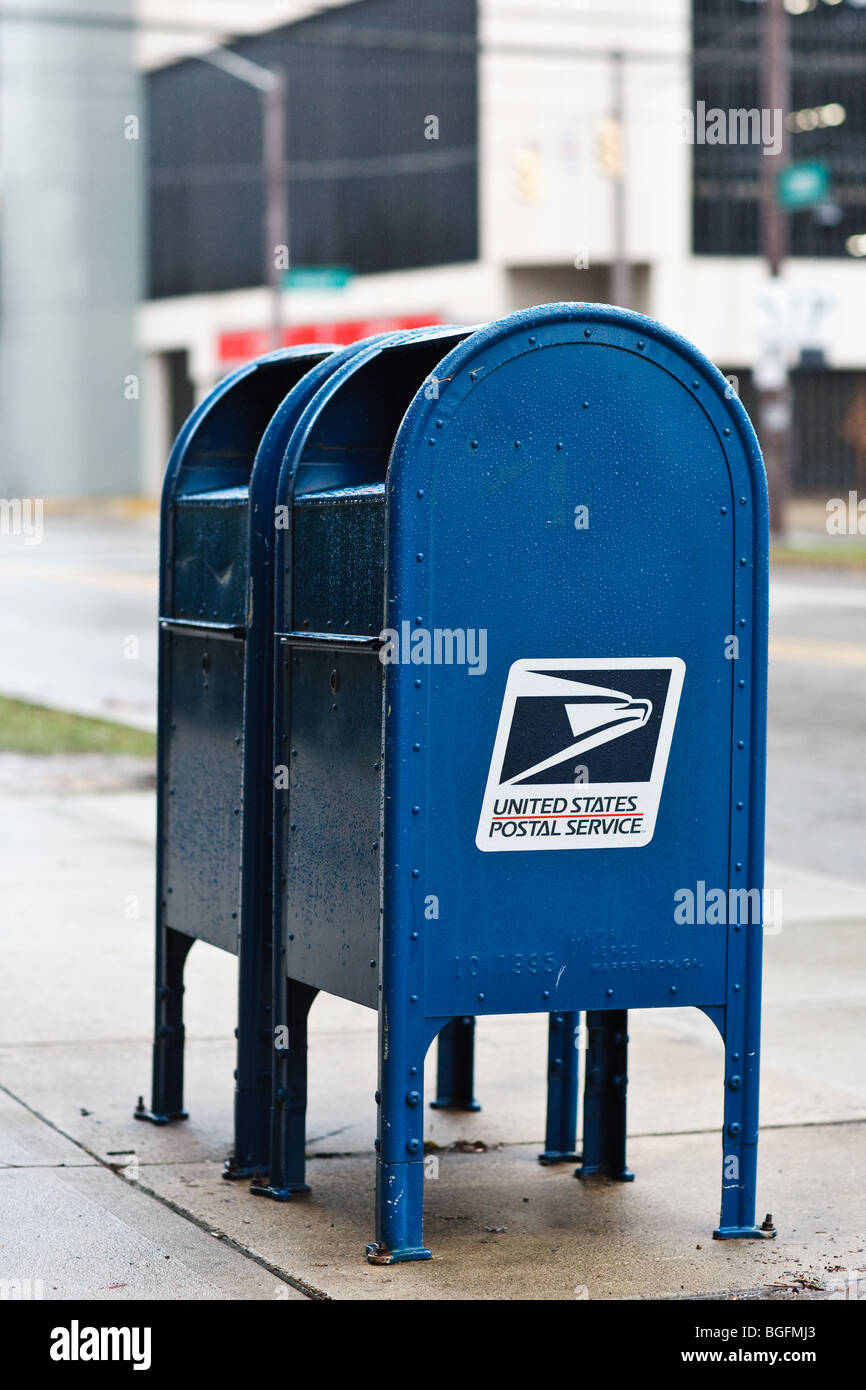 A pair of USPS mail boxes on a street corner on a rainy day Stock Photo