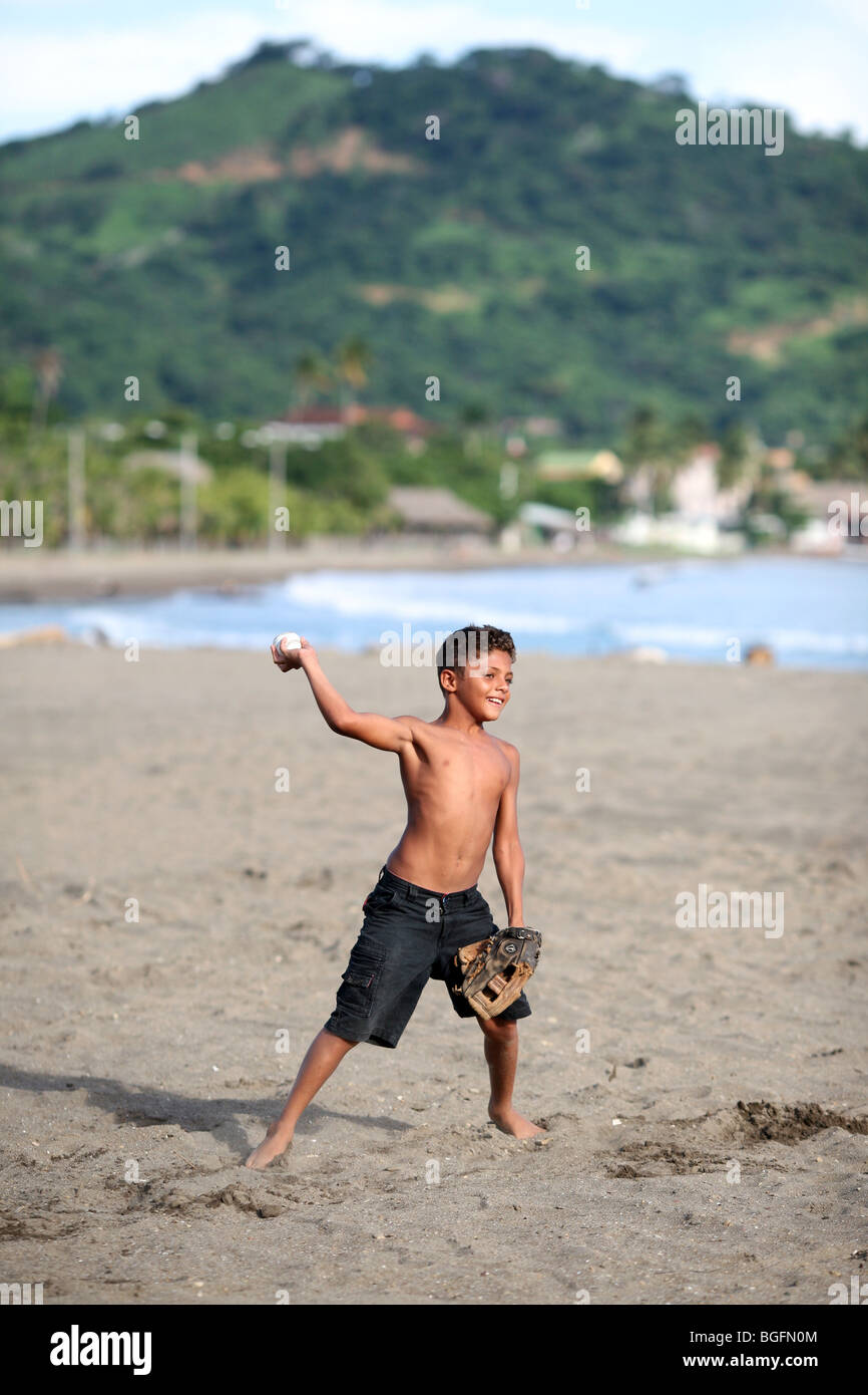 A boy throws a baseball during an afternoon game with his friends on the beach Stock Photo
