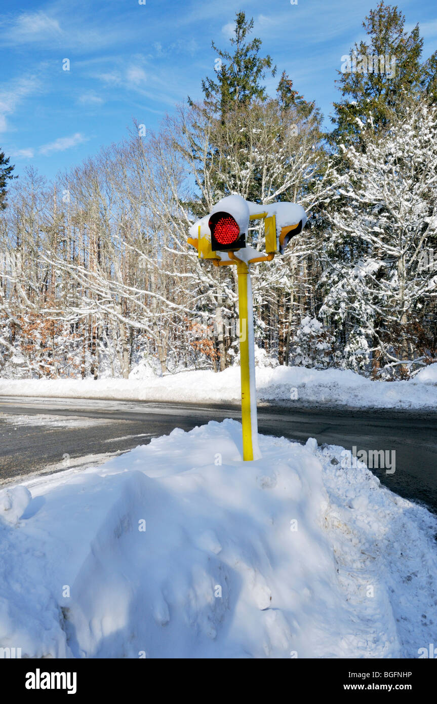 Red stop light in a snow bank on snowy winter road Stock Photo