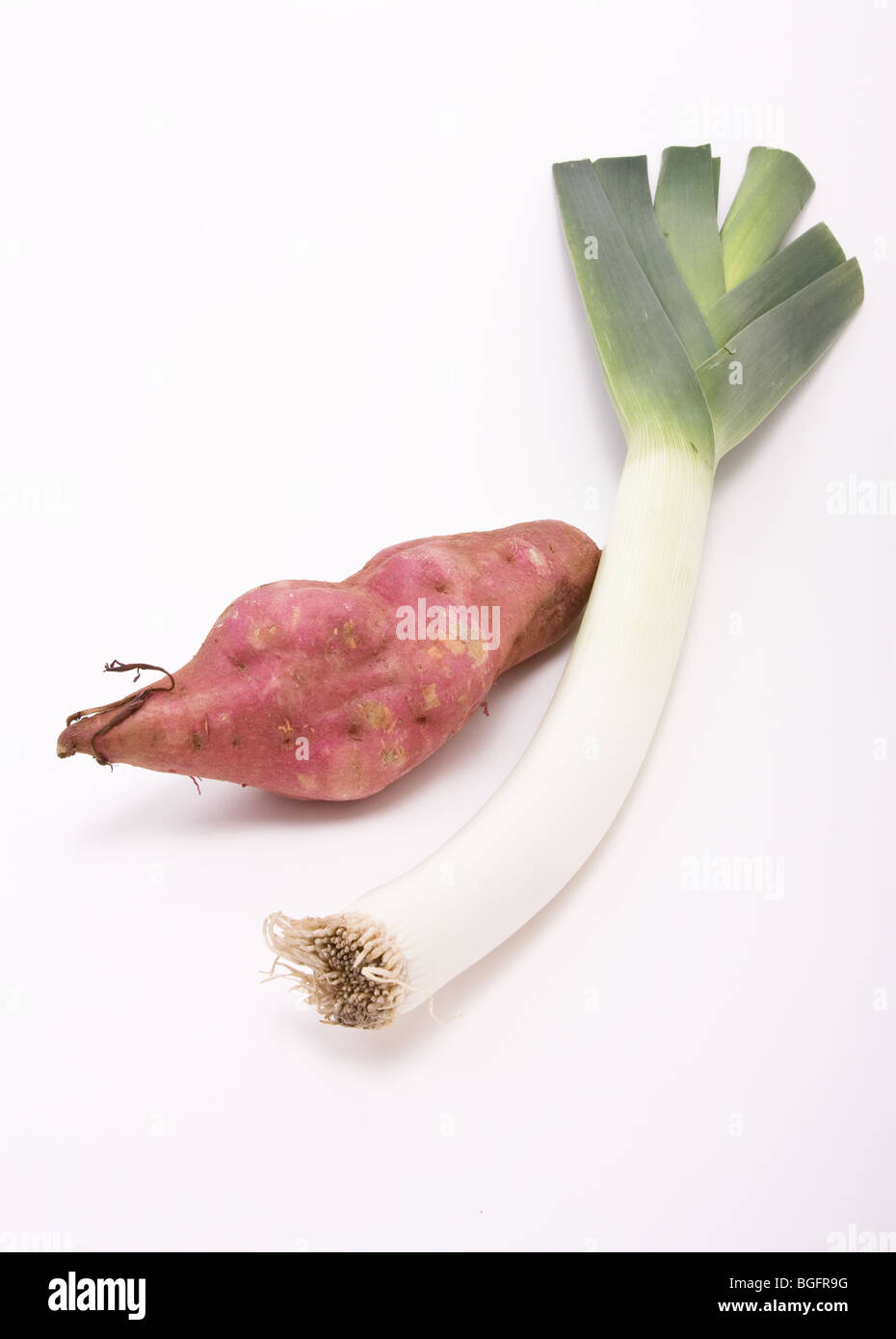 Sweet potato and Leek against white background from low perspective. Stock Photo