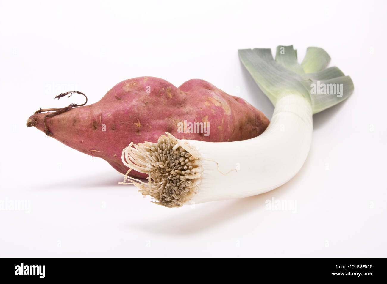 Sweet potato and Leek against white background from low perspective. Stock Photo
